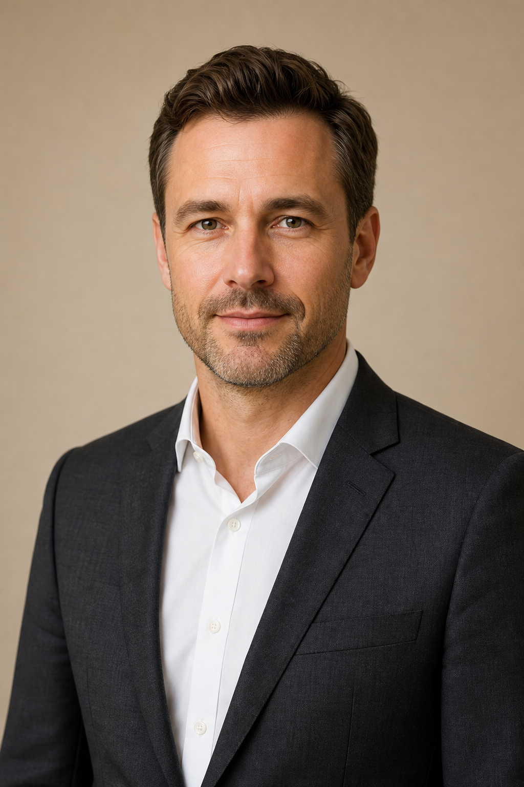 Corporate portrait of Daniel Brooks in a charcoal suit and white shirt on a neutral beige background